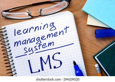 Notepad With Learning Management System LMS On Office Wooden Table.