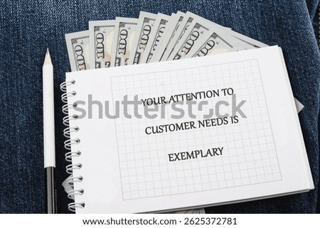A notepad with a message of appreciation sits on a pair of denim jeans alongside bundled cash, showcasing gratitude toward exemplary customer service in a business setting.