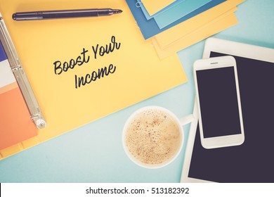 Notepad on workplace table and written BOOST YOUR INCOME concept