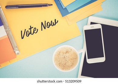 Notepad on workplace table and written VOTE NOW concept