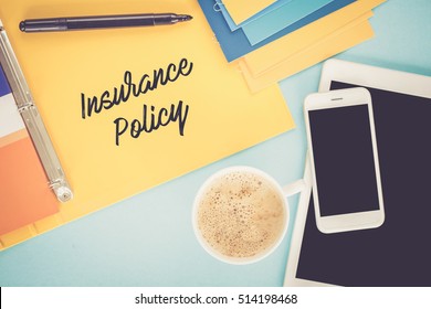 Notepad on workplace table and written INSURANCE POLICY concept
