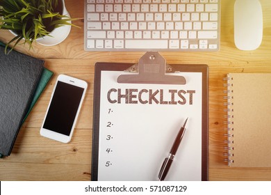 Notepad With A Paper Written CHECKLIST On Wooden Office Desk With Flare Effect                               