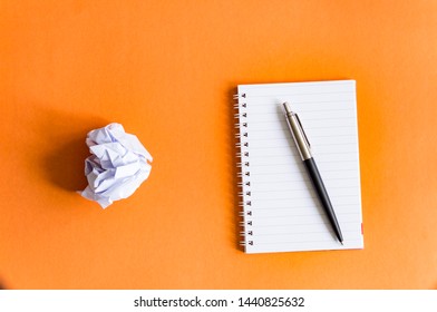 Notepad pen and crumpled into a lump of paper on an orange background, the concept of new and old ideas - Powered by Shutterstock