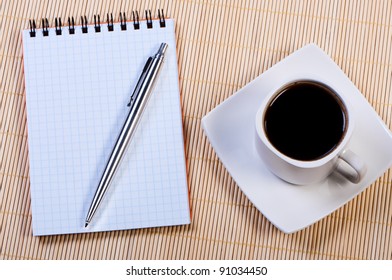 Notepad with pen and cup coffee.