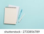 Notepad and pen on blue background. Flat lay with copy space.