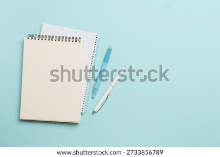 Notepad and pen on blue background. Flat lay with copy space.