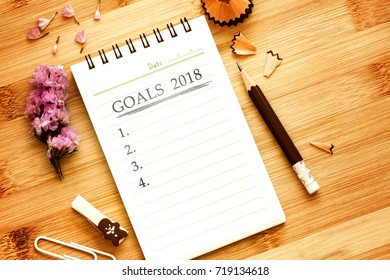 notepad with  pencil on wooden table for setting GOALS 2018 , new year plan concept , overhead shot or Top view