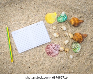 Notepad with pencil and starfish, shell on sand background or on the beach of sea using wallpaper for education photo.Take note of the product for book with paper concept or copy space and refreshing.