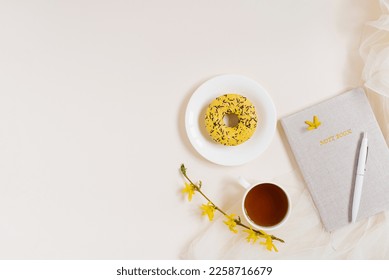 Notepad planner for business work with hot tea, a composition of flowers and donut on a beige background with copy space - Powered by Shutterstock