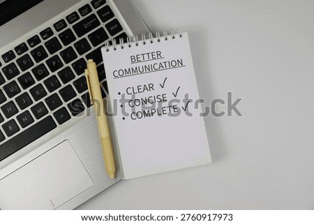 Notepad reading “Better Communication” with checklist items clear, concise and complete sits on a laptop keyboard beside a pen on white background, conveying workplace communication and productivity.