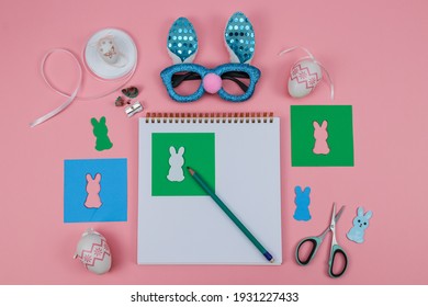 Notepad, Scissors, Glasses, Pencil, Colored Paper And A Rabbit On A Pink Background, Top View Close-up.