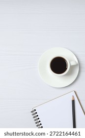 Notepad with spring on the table with pencil and coffee. Office concept. Top view.
