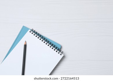 Notepad with spring on the table with pencil and coffee. Office concept. Top view.
