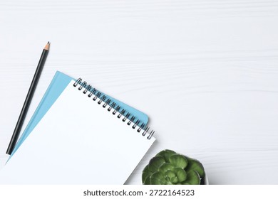 Notepad with spring on the table with pencil and coffee. Office concept. Top view.
