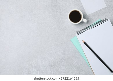 Notepad with spring on the table with pencil and coffee. Office concept. Top view.
