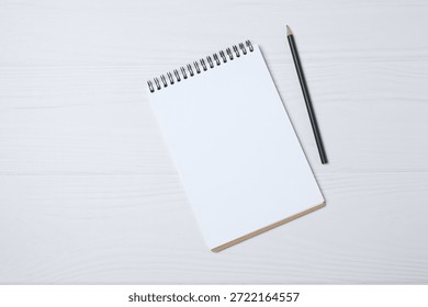 Notepad with spring on the table with pencil and coffee. Office concept. Top view.

