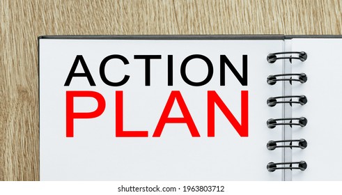 Notepad with text ACTION PLAN on wooden deskt. Business and finance concept