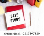 Notepad with the text CASE STUDY on a wooden table. Red diary and pen. Business concept.