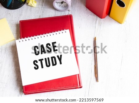 Notepad with the text CASE STUDY on a wooden table. Red diary and pen. Business concept.