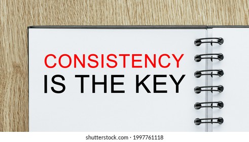 Notepad with text Consistency is the key on wooden deskt. Business and finance concept