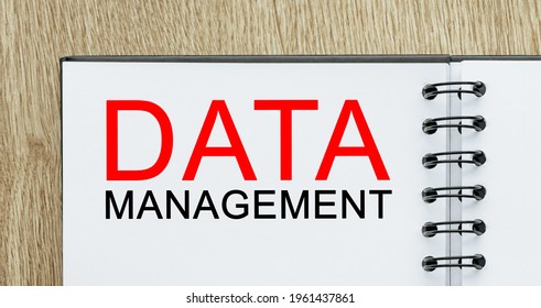 Notepad with text DATA MANAGEMENT on wooden deskt. Business and finance concept