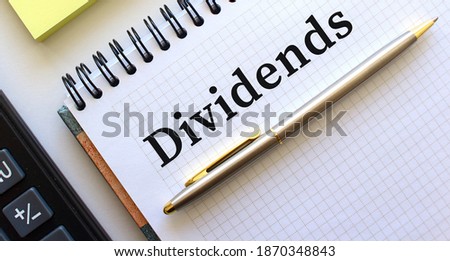 Notepad with text DIVIDENDS, next to it lies a calculator. Business concept.