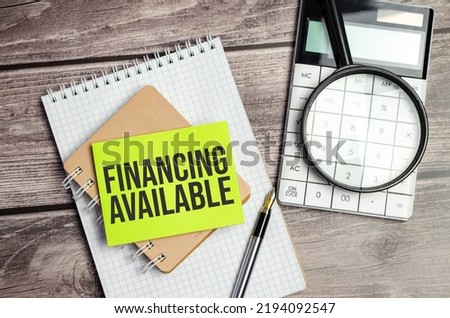 Notepad with text financing available on wooden background