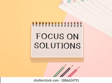 Notepad with text FOCUS ON SOLUTIONS on a white background, near calculator and yellow note papers. Business concept.