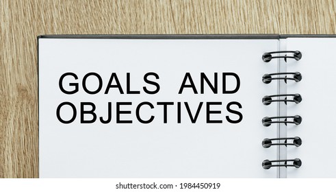 Notepad with text Goals and Objectives on wooden deskt. Business and finance concept