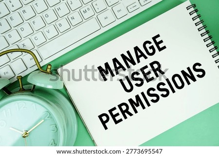 Notepad with the text "Manage User Permissions" and white keyboard and alarm clock on green background