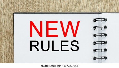 Notepad with text new rules on wooden deskt. Business and finance concept