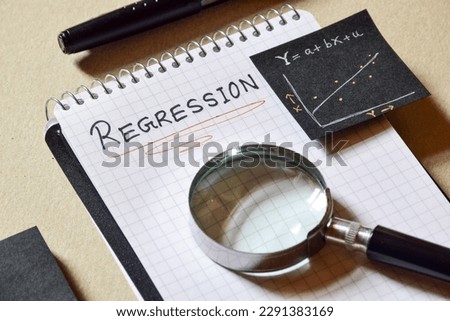 Notepad with the text Regression and it's formula and analysis graph on desk. 