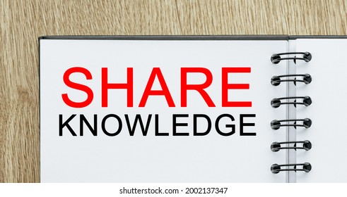 Notepad with text SHARE KNOWLEDGE on wooden deskt. Business and finance concept