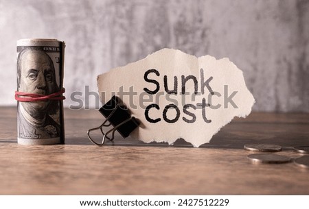 Notepad with the text SUNK COST on a white background. And the word ZERO on the cubes.