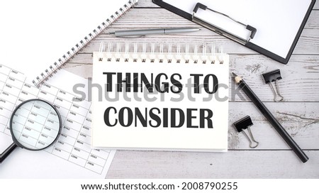 Notepad with text Things To Consider with a pen,office tools and graphs on desktop.