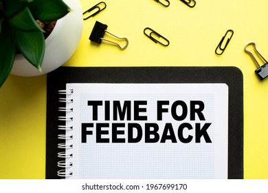 Notepad with text TIME FOR FEEDBACK on the office desk with a plant, stationery. A blank notepad for entering a copy or text. Table with top view, flat yellow background concept. business