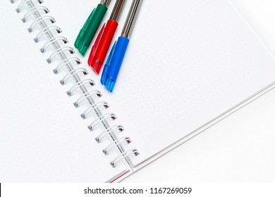 Notepad with white background and three colored pens