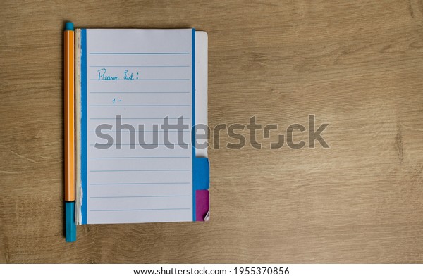 Notepad with white pages with an orange body pen\
and blue ink on an office desk used for home office. Written in\
detail mentioning a list of reasons. Different color tabs to divide\
subjects by color.