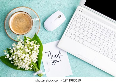 Notes thank you, coffee cup, laptop, bouquet of flowers lily of the valley on desk. Workplace in home office laptop and thank you note. Thankfulness, customer service, thanks card concept