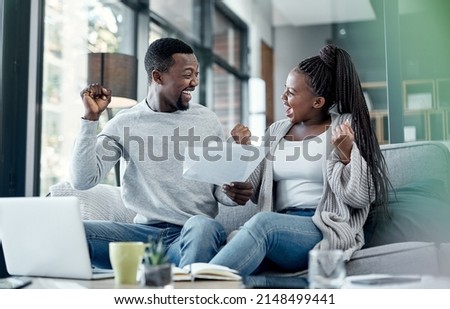 Nothing feels better than being debt free. Shot of a young couple celebrating while going through paperwork at home.