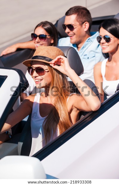 Nothing but friends\
and road trip. Top view of young happy people enjoying road trip in\
their white convertible