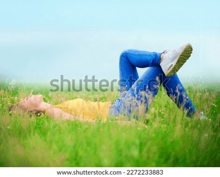 Nothing like a day of doing nothing. a young woman lying down in a field of grass.