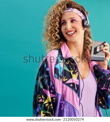 Nothing makes me feel as good as 80s music. Studio shot of a young woman holding a cassette player while dressed in 80s clothing.
