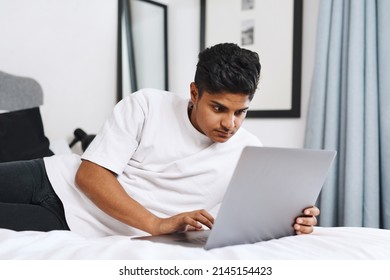 Nothing Passes The Time Like Some Cyber Stalking. Cropped Shot Of An Young Man Using His Laptop While Lying On His Bed.