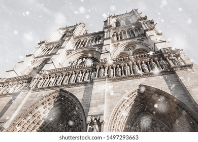 Notre Dame cathedral in Paris, France in gloomy winter day in snowstorm. Upward glance. Pastel trendy toning. Beautiful inspiring moody faded scenery