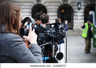 NOTTINGHAM, UK - APRIL 28, 2011: Young female reporter prepares audio-video equipment for street interview 