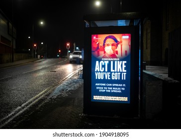 Nottingham UK, January 27th 2021 Coronavirus Light Up Government Warning Information Sign On Bus Stop Shelter With Cars Passing At Night In Darkness Lit Up Illuminated Covid 19 Act Like You Have It