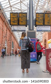 Nottingham, United Kingdom. 3 June 2019. TYoung girl looking at timetable departure board at Nottingham train station.