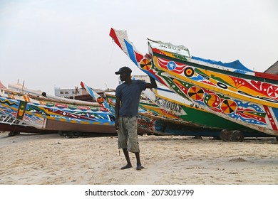 Nouakchott, Mauritania - October 2021: fishermen and their painted wooden boats on Atlantic ocean beach near Nouakchott