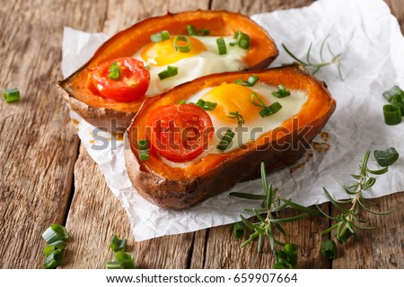 Nourishing food: stuffed sweet potato with fried egg and tomato close-up on the table. horizontal
